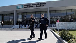 Agenti della polizia greca camminano fuori dalla Galleria Nazionale, mentre Nikolaos Papadopoulos, membro del parlamento del piccolo partito di destra Niki, viene arrestato