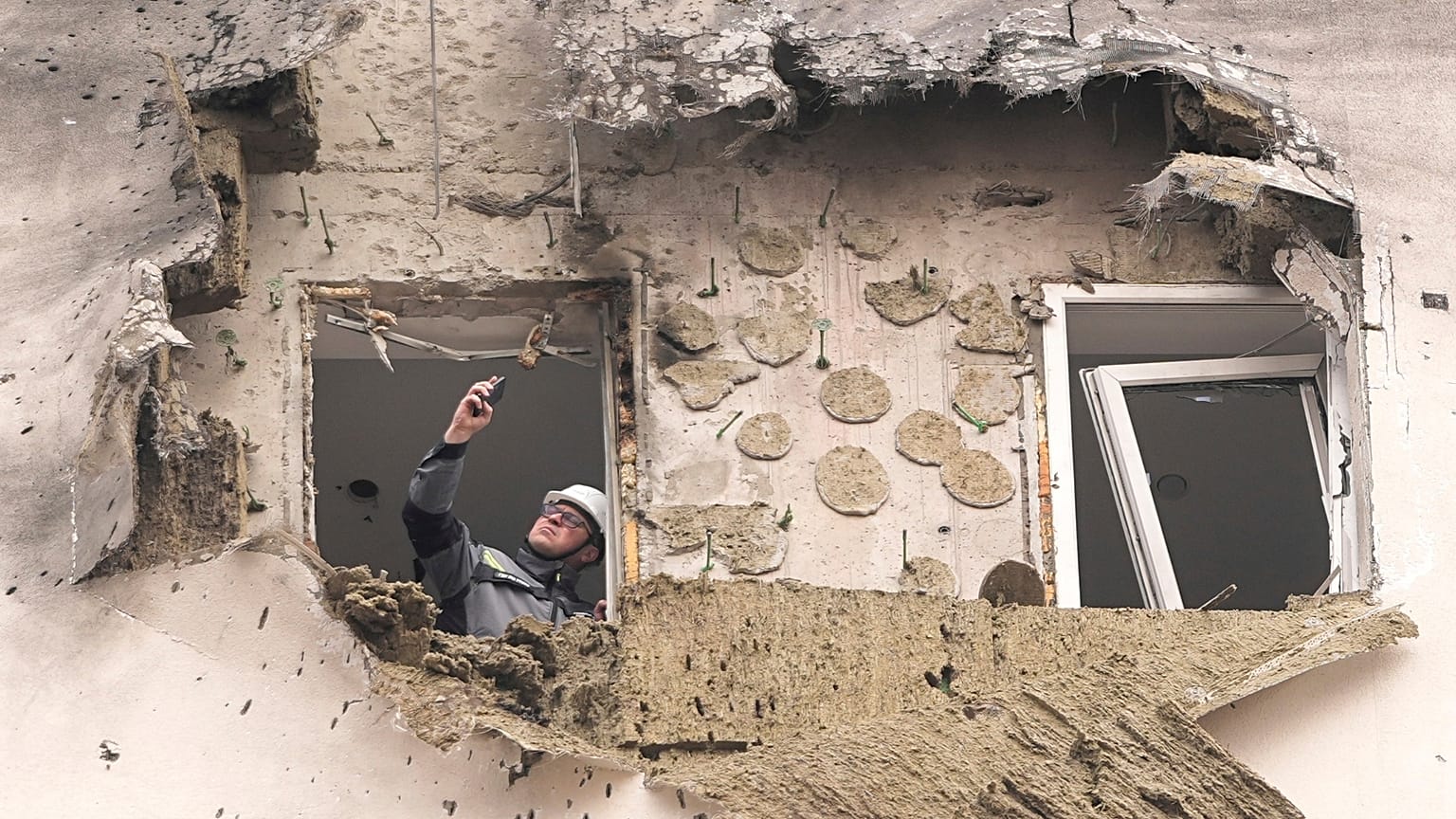 A investigator looks at the damage of an apartment building where a downed Ukrainian drone fell in Sapronovo village outside Moscow, Russia, on Tuesday, March 11, 2025.