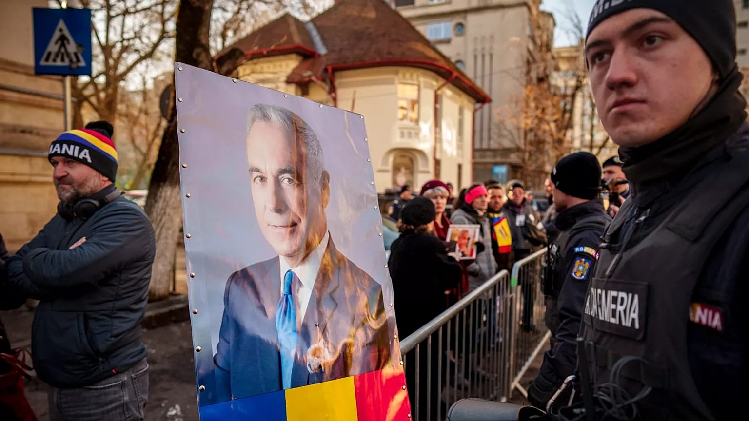 FILE: Un ritratto di Calin Georgescu viene posto su un recinto di controllo della folla dai sostenitori che attendono il suo arrivo presso un tribunale distrettuale a Bucarest, 5 marzo 2025