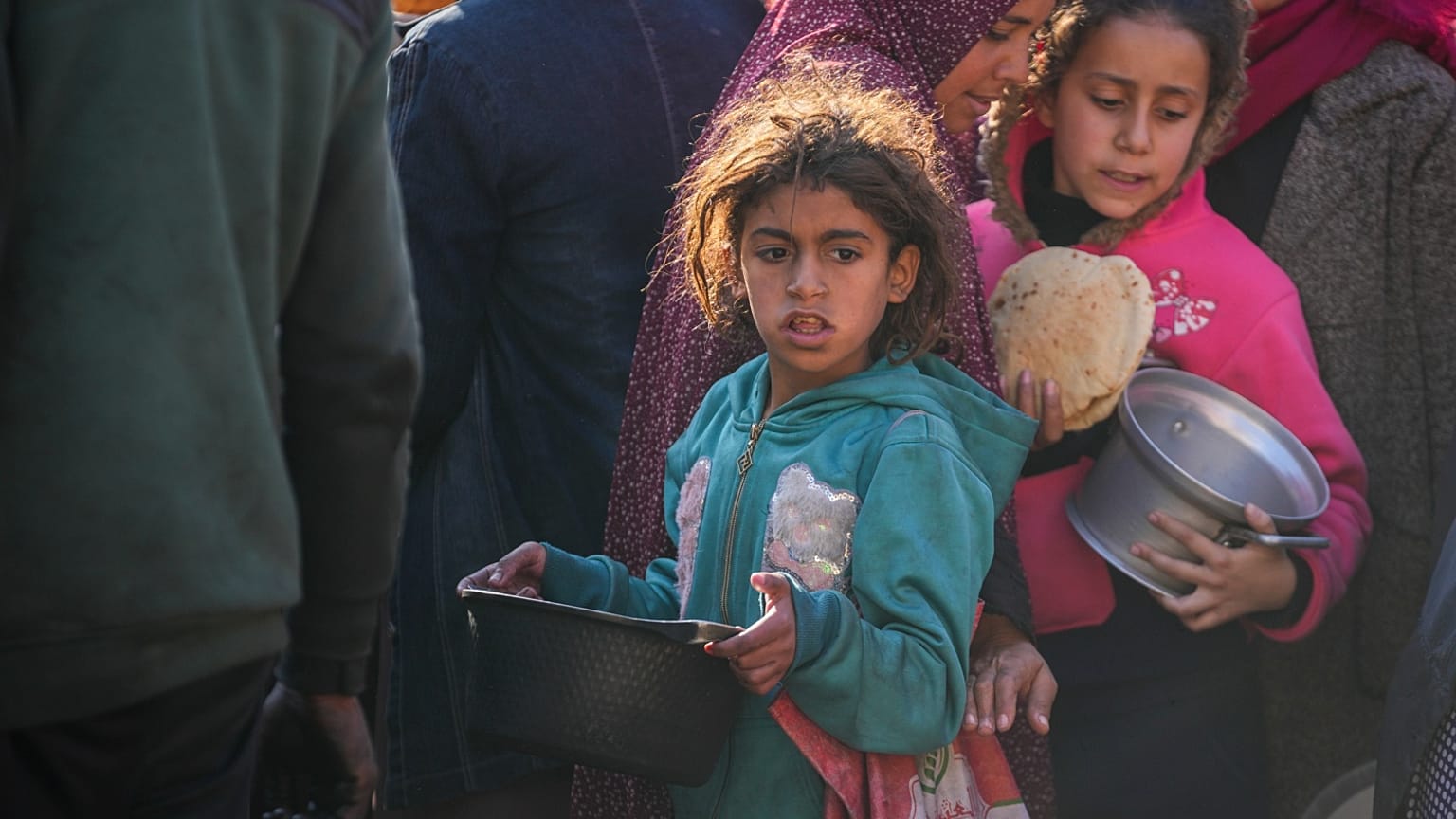 فتيات فلسطينيات يجمعن الطعام في مركز توزيع الأغذية في دير البلح، وسط قطاع غزة، الخميس 2 يناير 2025