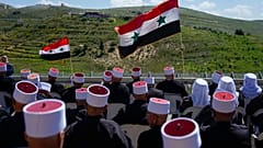 رجال دروز يجلسون حاملين الأعلام السورية خلال مسيرة بمناسبة عيد استقلال سوريا، في قرية مجدل شمس الدرزية في مرتفعات الجولان التي تسيطر عليها إسرائيل، الاثنين، 17 أبريل/نيسان 202
