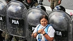 Eine Frau steht während eines Protests gegen die von der Regierung von Javier Milei in Buenos Aires, Argentinien, am 12. März 2025 umgesetzten Sparmaßnahmen vor der Riot-Polizei.