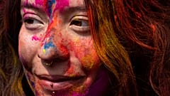 Eine Touristin hat ihr Gesicht während Holi, dem hinduistischen Farbenfest am Basantapur Durbar Platz in Kathmandu, Nepal, am Donnerstag, den 13. März 2025, mit farbigem Pulver bedeckt.