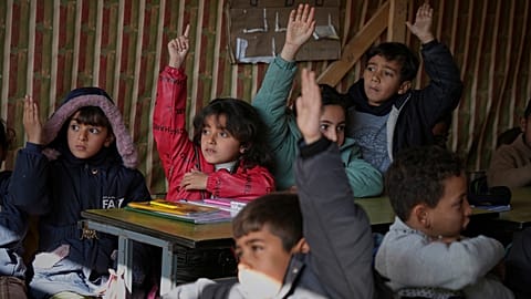 Niños palestinos reciben una lección en un aula improvisada ubicada dentro de un recinto escolar, en la ciudad de Gaza, 10 de marzo de 2025.