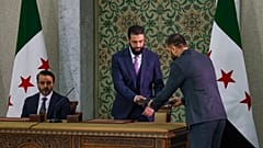 Ο προσωρινός πρόεδρος της Συρίας Ahmad Al-Sharaa, στο κέντρο, ετοιμάζεται να υπογράψει ένα προσωρινό σύνταγμα για τη χώρα στη Δαμασκό.
