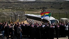 رجال دين دروز يستقبلون حافلات تقل أبناء الطائفة الدرزية السورية على الحدود مع سوريا، أثناء دخولهم إلى قرية مجدل شمس، الجمعة، 14 مارس/آذار 2025