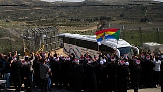رجال دين دروز يستقبلون حافلات تقل أبناء الطائفة الدرزية السورية على الحدود مع سوريا، أثناء دخولهم إلى قرية مجدل شمس، الجمعة، 14 مارس/آذار 2025