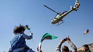 طائرة هليكوبتر تابعة للجيش السوري ترمي الزهور على مجموعة من المتظاهرين في الذكرى الرابعة عشرة لبدء "الثورة السورية" ضد نظام بشار الأسد، دمشق، سوريا، السبت 15 مارس 2025.
