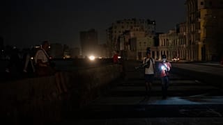 Küba'nın Havana kentinde 14 Mart 2025 Cuma günü yaşanan genel elektrik kesintisi sırasında kent sakinleri bir caddede yürüyor. (AP Fotoğrafı/Ramon Espinosa)