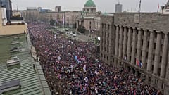 Des manifestants agitent des drapeaux serbes devant le parlement serbe lors d'un grand rassemblement anti-corruption mené par des étudiants à Belgrade, Serbie, le 15 mars 2025.