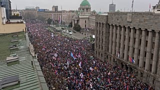Протестующие размахивают сербскими флагами у здания парламента во время крупного антикоррупционного митинга в Белграде, Сербия, 15 марта 2025 года.