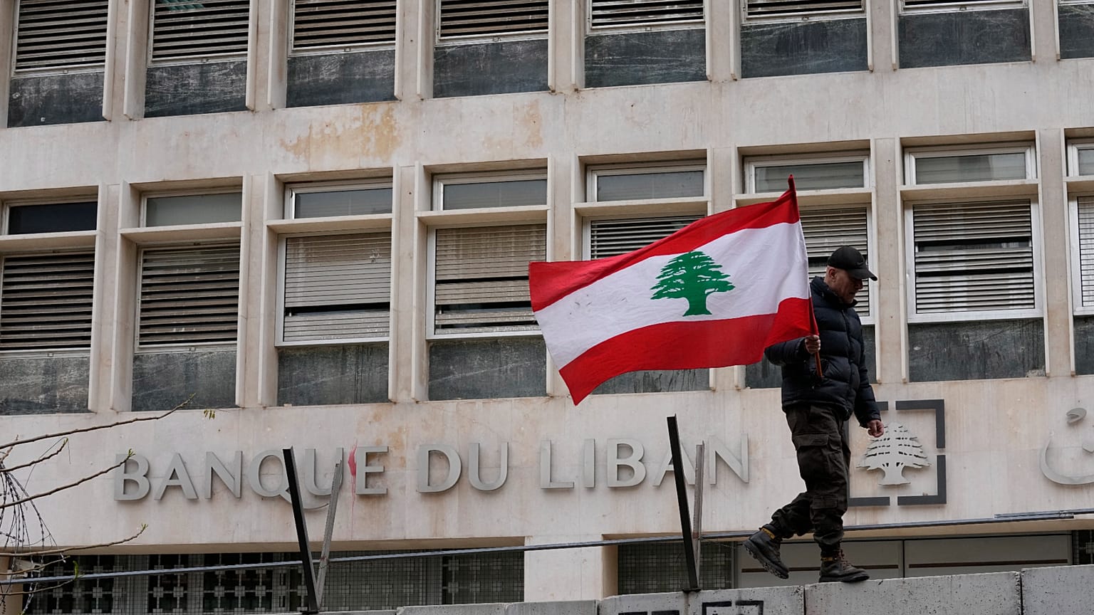 جندي متقاعد يحمل العلم اللبناني  أمام المصرف المركزي خلال مظاهرة للمطالبة بتحسين الأجور والظروف المعيشية، في بيروت، لبنان، الخميس، 30 مارس/آذار 2023