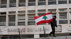 جندي متقاعد يحمل العلم اللبناني  أمام المصرف المركزي خلال مظاهرة للمطالبة بتحسين الأجور والظروف المعيشية، في بيروت، لبنان، الخميس، 30 مارس/آذار 2023