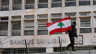 جندي متقاعد يحمل العلم اللبناني  أمام المصرف المركزي خلال مظاهرة للمطالبة بتحسين الأجور والظروف المعيشية، في بيروت، لبنان، الخميس، 30 مارس/آذار 2023