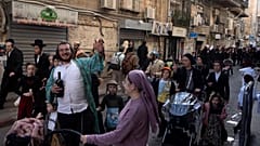رجال وأطفال يهود، بعضهم يرتدي أزياء تنكرية، يحتفلون بعيد المساخر اليهودي في حي ميا شيريم الأرثوذكسي في القدس، الاثنين، 25 مارس 2024.