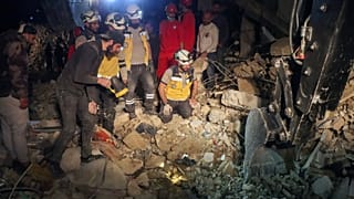   فريق الدفاع المدني السوري ”الخوذ البيضاء“ يبحثون بين أنقاض مبنى مكون من أربعة طوابق بعد انفجار قذيفة في مدينة اللاذقية الساحلية في سوريا، يوم الأحد 16 مارس/آذار 2025. 2025