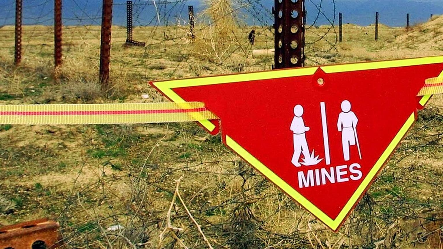 Una señal internacional de advertencia sobre minas cuelga junto a un campo de minas en la base aérea de Bagram, Afganistán, 22 de marzo de 2002. 