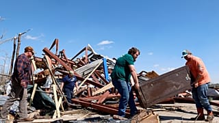 Freunde und Familie tragen einen Safe aus dem beschädigten Gebäude, nachdem ein Tornado am Sonntag, den 16. März 2025, durch die Gegend gezogen ist, in Plantersville, Alabama.
