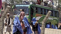Uma família afegã caminha para o seu autocarro de partida para o Afeganistão num terminal de repatriamento do ACNUR em Peshawar, Paquistão, em 24 de maio de 2009. 