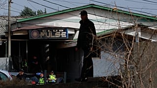 Сотрудник полиции осматривает помещение клуба "Пульс" после пожара в городе Кочаны, 16 марта 2025 года