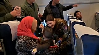 Crianças e membros da tripulação brincam no interior de um avião KC 767 da Força Aérea Italiana