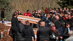 Särge stehen neben den Gräbern, während sich Menschen auf einem Friedhof zur Beerdigungszeremonie der Opfer eines massiven Nachtclubbrandes in Nordmazedonien versammeln, am 20. März 2025.