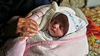 إيلا أسامة أبو دقة، البالغة من العمر 25 يومًا، تحملها عمتها سعاد أبو دقة، بعد إنقاذها من تحت الأنقاض عقب غارة جوية شنها الجيش الإسرائيلي، في خان يونس، 20 آذار/مارس 2025.