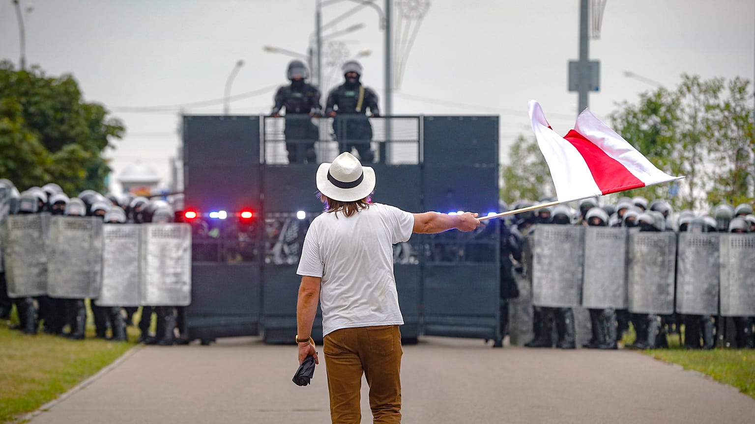 Der Künstler Ales Pushkin schwenkt eine rot-weiße Flagge, die die oppositionelle Lukaschanka symbolisiert, vor einer Polizeisperre während einer Demonstration in Minsk, Belarus 23.08.2020