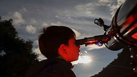FILE - A youth looks through a telescope during a stargazing and comet-watching gathering.