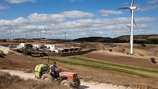 A man drives a tractor through a wind farm in Sobral de Monte Agraco north of Lisbon, 13 August, 2015