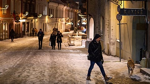 A person with a dog walks through the snow-covered Old Town in Vilnius, Lithuania, 17 February 2025.