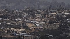 أشخاص يسيرون وسط المنازل المدمرة خلال الهجوم الجوي والبري الإسرائيلي على قطاع غزة من جنوب إسرائيل، الخميس، 20 مارس/آذار 2025