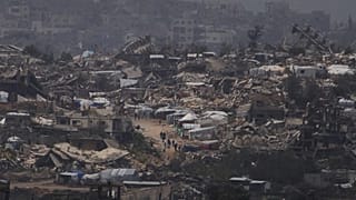 أشخاص يسيرون وسط المنازل المدمرة خلال الهجوم الجوي والبري الإسرائيلي على قطاع غزة من جنوب إسرائيل، الخميس، 20 مارس/آذار 2025
