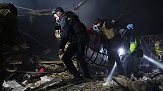 Сотрудники полиции несут тело человека, погибшего в результате удара российского беспилотника, в жилом квартале в Запорожье, Украина, пятница, 21 марта 2025 года.