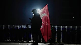 İmamoğlu'nun tutuklanmasına karşı düzenlenen protesto sırasında çevik kuvvet polisi nöbet tutarken bir protestocu, 23 Mart günü Çağlayan Adliyesi dışında görüntüleniyor.