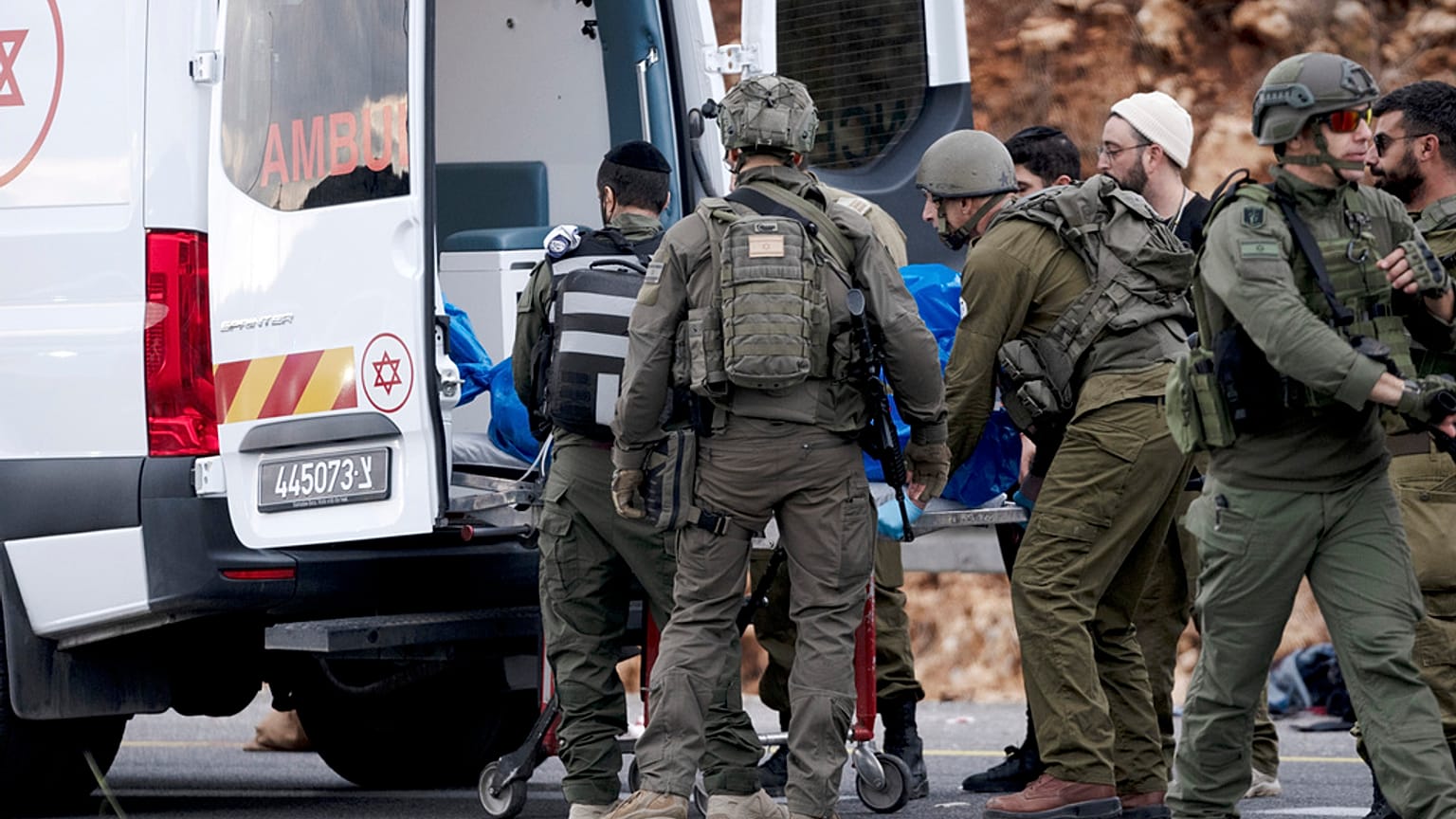 جنود إسرائيليون ينقلون جثة مسلح فلسطيني مشتبه به إلى سيارة إسعاف بعد هجوم إطلاق نار استهدف حافلة إسرائيلية الضفة الغربية، الجمعة، 29 نوفمبر/تشرين الثاني 2024.