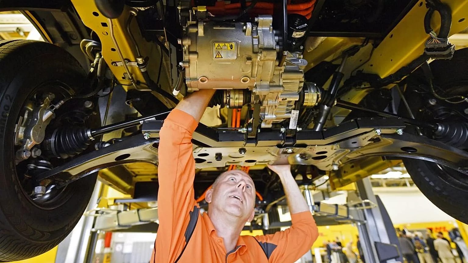 Um trabalhador observa o pequeno motor elétrico por baixo de uma nova carrinha de entregas eléctrica Deutsche Post StreetScooter Work XL na fábrica de automóveis da Ford em Colónia, Alemanha, 9 de outubro de 2018.