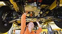 Um trabalhador observa o pequeno motor elétrico por baixo de uma nova carrinha de entregas eléctrica Deutsche Post StreetScooter Work XL na fábrica de automóveis da Ford em Colónia, Alemanha, 9 de outubro de 2018.
