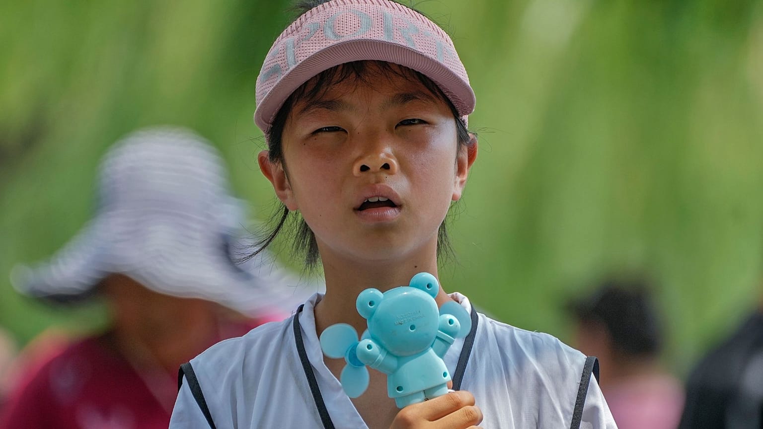 Un niño sostiene un ventilador eléctrico mientras reacciona al calor durante una visita a la Ciudad Prohibida de Pekín, 8 de julio de 2024. 