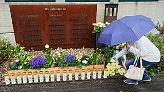 Eine Frau legt während einer Gedenkfeier auf dem Schulhof des Joseph-Koenig-Gymnasiums in Haltern, Deutschland, eine Rose nieder.