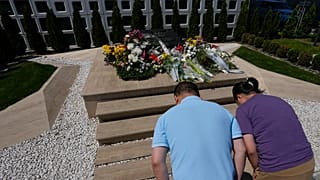 زائرون من الصين ينحنون أمام نصب تذكاري من الرخام الأسود ويضعون الزهور تكريماً لضحايا تفجير عام 1999، في بلغراد، صربيا، السبت 4 مايو/أيار 2024. 