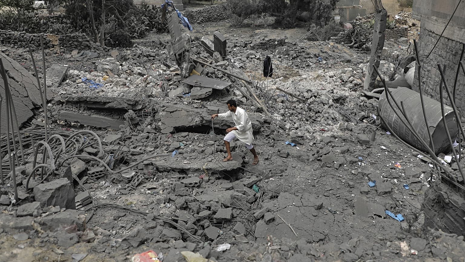 Uno yemenita cammina sulle macerie di un edificio distrutto a Sanaa
