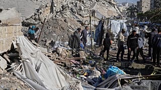 Палестинцы осматривают место, пострадавшее от израильской бомбардировки, в городе Газа в воскресенье, 23 марта 2025 года.