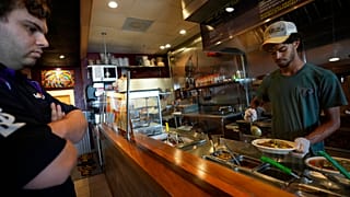 Keval Bodasing, 17, prepares an order for customer Adrian Lopez, as he helps out his father, Anesh Bodasing, at his fast-casual Indian restaurant, Tiffin Box, in Florida, US. 