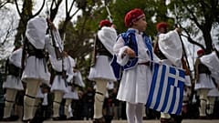 Uma criança vestida como um Evzonas segura uma bandeira grega diante da Guarda Presidencial em Atenas, antes de um desfile que marca o Dia da Independência da Grécia, na terça-feira, 25 de março de 2025.