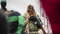 Боец ХАМАС в боевом обмундировании стоит на церемонии передачи израильских заложников Красному Кресту в Нусейрате, 22 февраля 2025 г.
