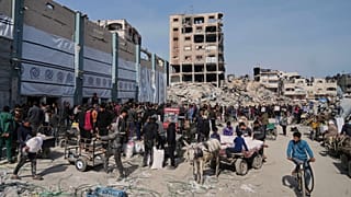 Algunos palestinos reciben bolsas de harina y ayuda humanitaria distribuida por la UNRWA, la agencia de la ONU que ayuda a los refugiados en Jabaliya, en la Franja de Gaza.