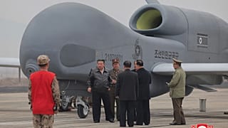 El líder norcoreano Kim Jong-un, en el centro a la izquierda, junto a lo que parece ser un gran dron de reconocimiento en un lugar no revelado de Corea del Norte.