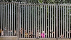 Des demandeurs d'asile regardent à travers les grilles d'un mur construit par la Pologne à sa frontière avec la Biélorussie, à Bialowieza, en Pologne, le 28 mai 2023.