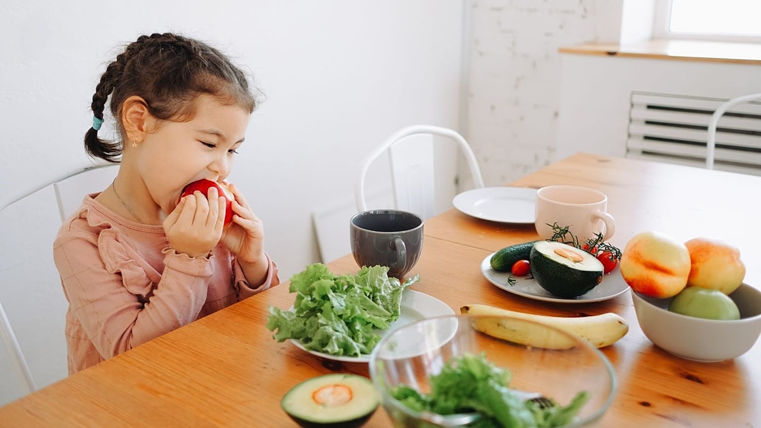Una niña come una fruta.